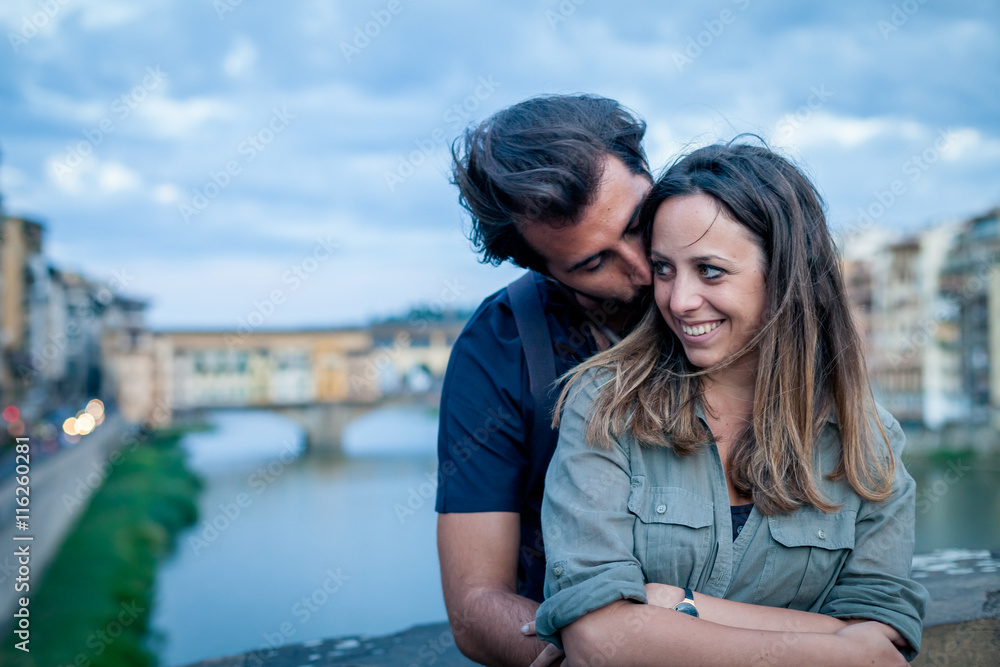 Loving couple embracing at the sunset in front of Ponte Vecchio, Florence Loving couple embracing at the sunset in front of Ponte Vecchio, Florence