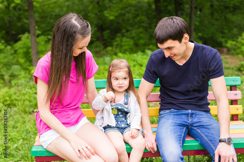 young family sitting on a bench in the summer park © satura_