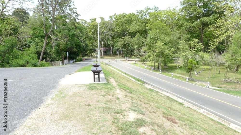 scenic of the road, tree and wooden seat in the park (panning right) scenic of the road, tree and wooden seat in the park (panning right)