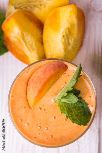 Smoothie in a glass and slices of fresh peaches