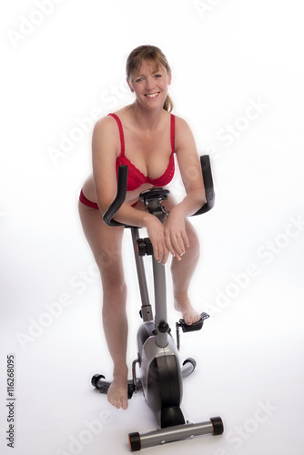 WOMAN RIDING AN EXERCISE BIKE - A mid age woman wearing red underwear riding an exercise bicycle