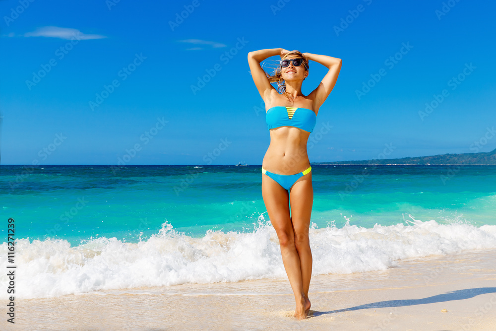 Young beautiful girl in blue bikini having fun on a tropical bea