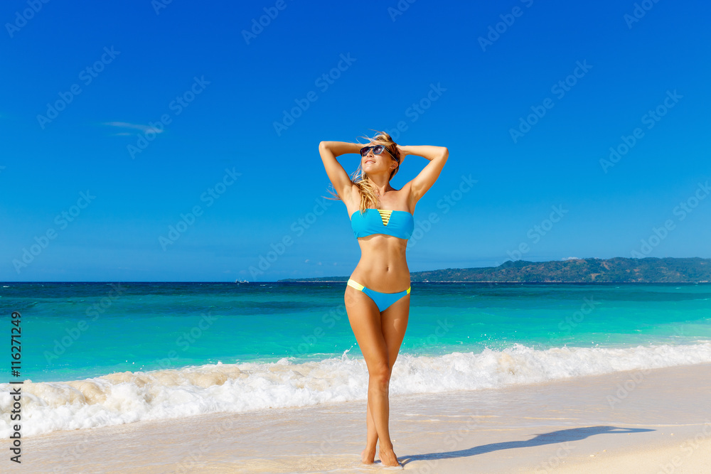 Young beautiful girl in blue bikini having fun on a tropical bea Young beautiful girl in blue bikini having fun on a tropical bea