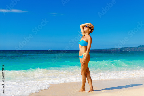 Young beautiful girl in blue bikini having fun on a tropical bea