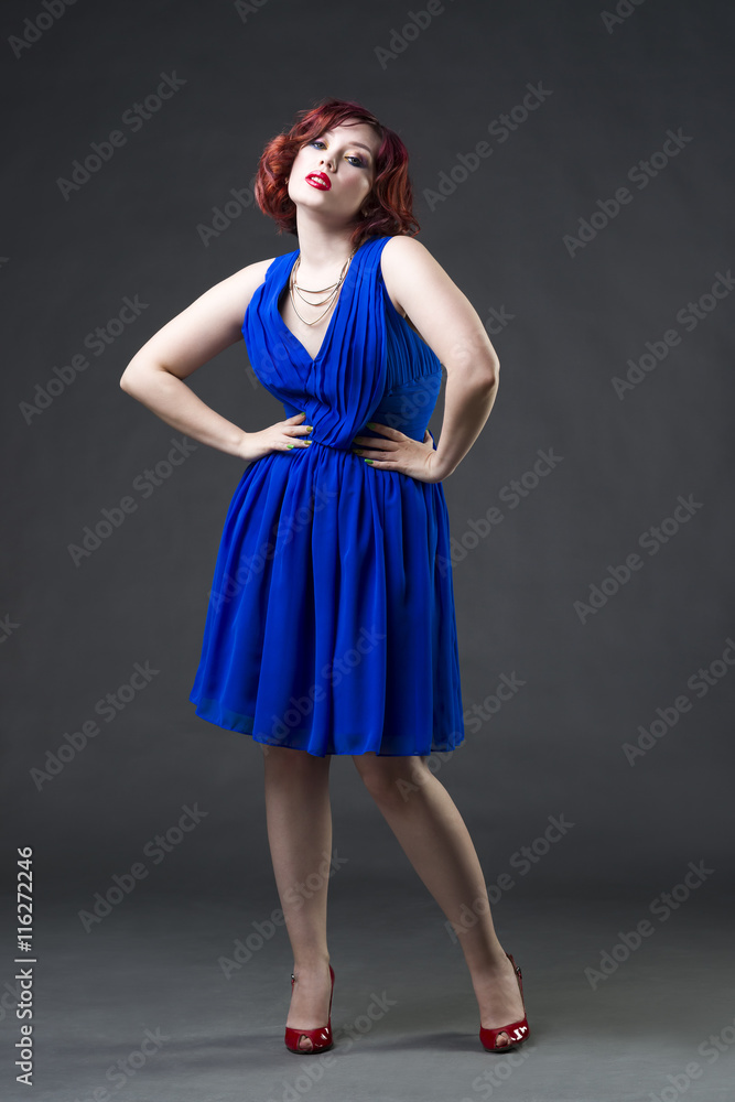 Young beautiful red-haired caucasian woman in blue dress posing in studio on gray background, professional makeup and hairstyle Young beautiful red-haired caucasian woman in blue dress posing in studio on gray background, professional makeup and hairstyle