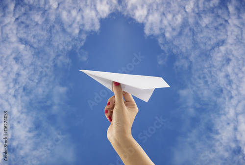 Hand holding paper plane on sky background