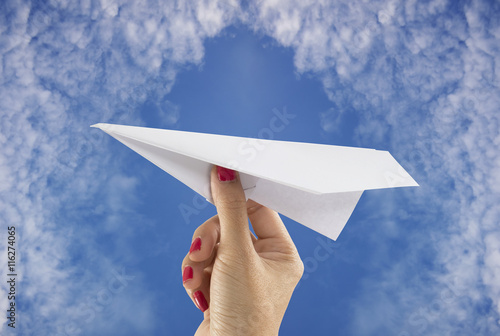 Hand holding paper plane on sky background