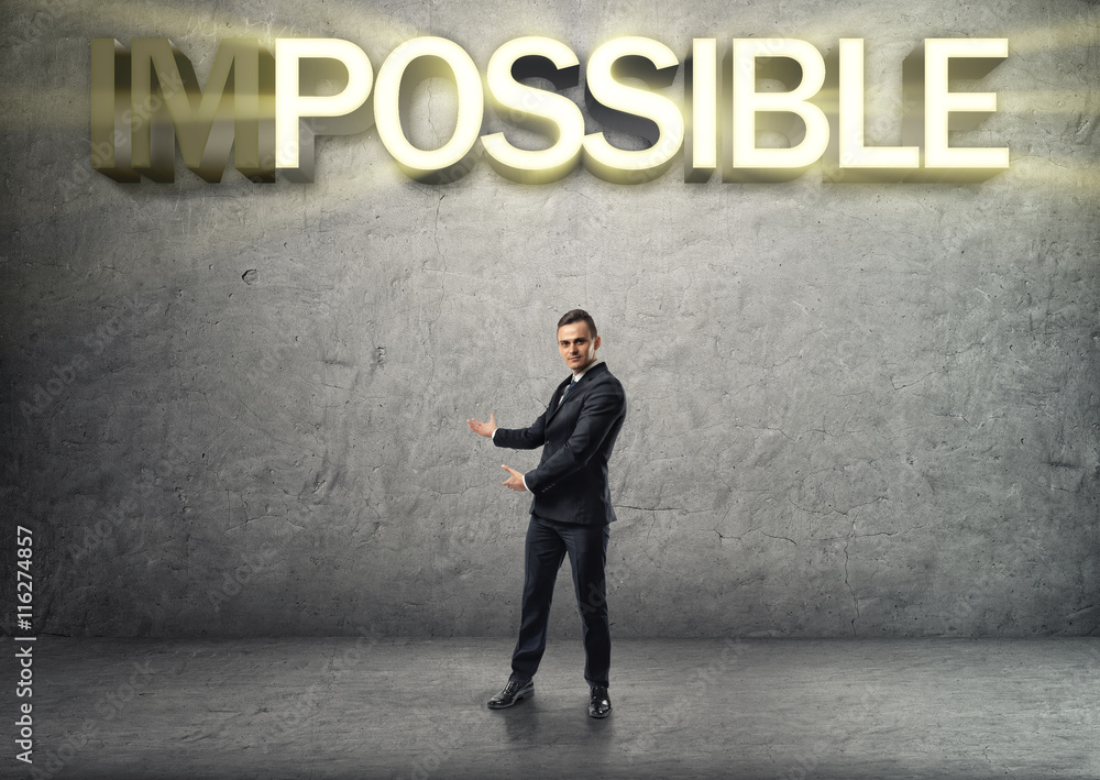 Businessman stands showing the word by both hands on the concrete background Businessman stands showing the word by both hands on the concrete background