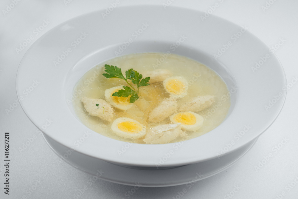 Chicken soup in a white plate with eggs and greens Chicken soup in a white plate with eggs and greens