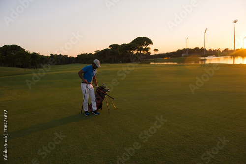 golfer walking and carrying golf bag at beautiful sunset