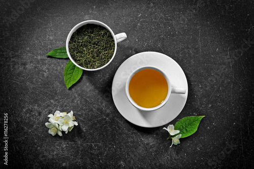 Cup of tea with jasmine flowers on color background
