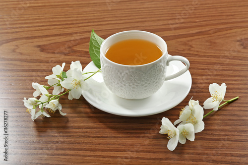 Cup of tea with jasmine flowers on wooden background
