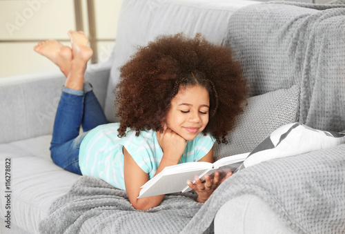 Cute African girl reading b...