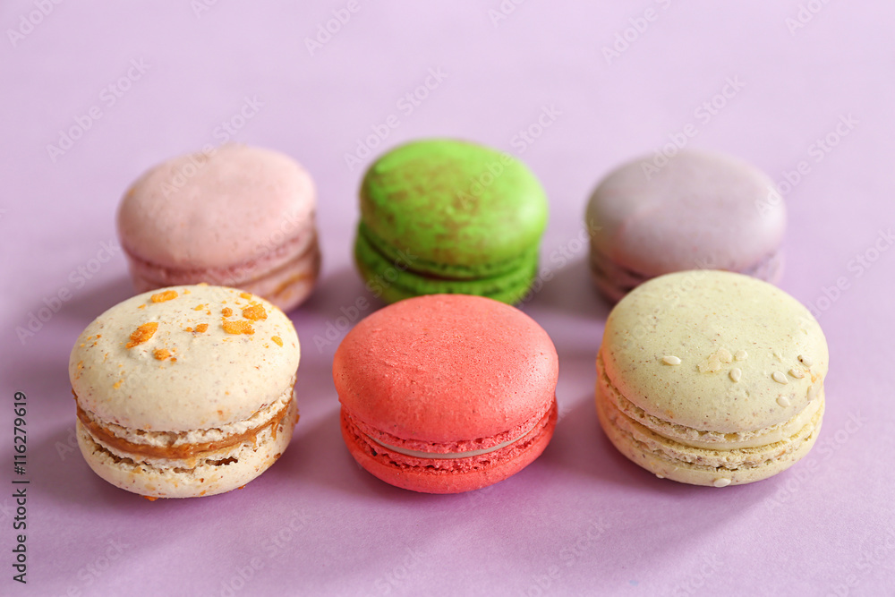 Colorful tasty macaroons in row on purple background Colorful tasty macaroons in row on purple background