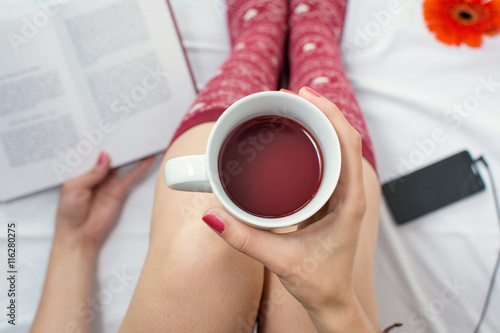 Woman reading a book and having cup of tea