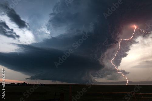 Fototapeta Extreme supercell thunderstorm with vivid lightning at dusk over tornado alley
