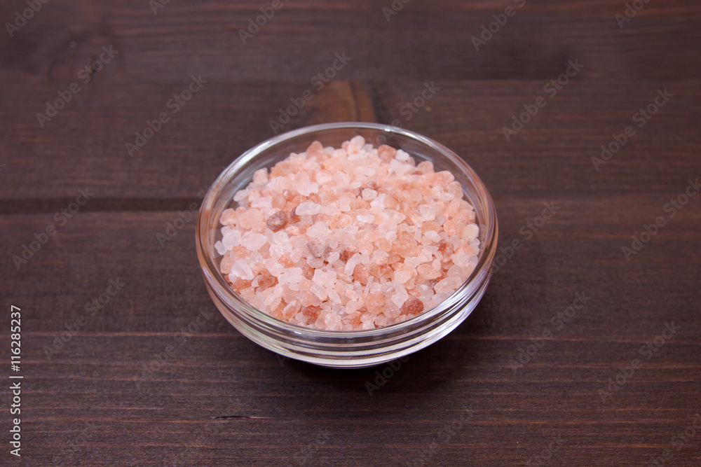 Himalayan pink salt to bowl on a wooden table Himalayan pink salt to bowl on a wooden table