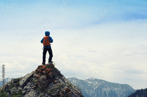 successful woman backpacke hiking on mountain peak cliff