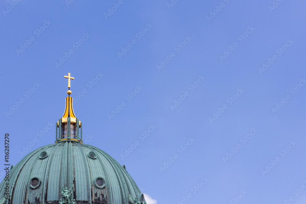 Top of Berlin Cathedral, golden cross and blue sky copy space