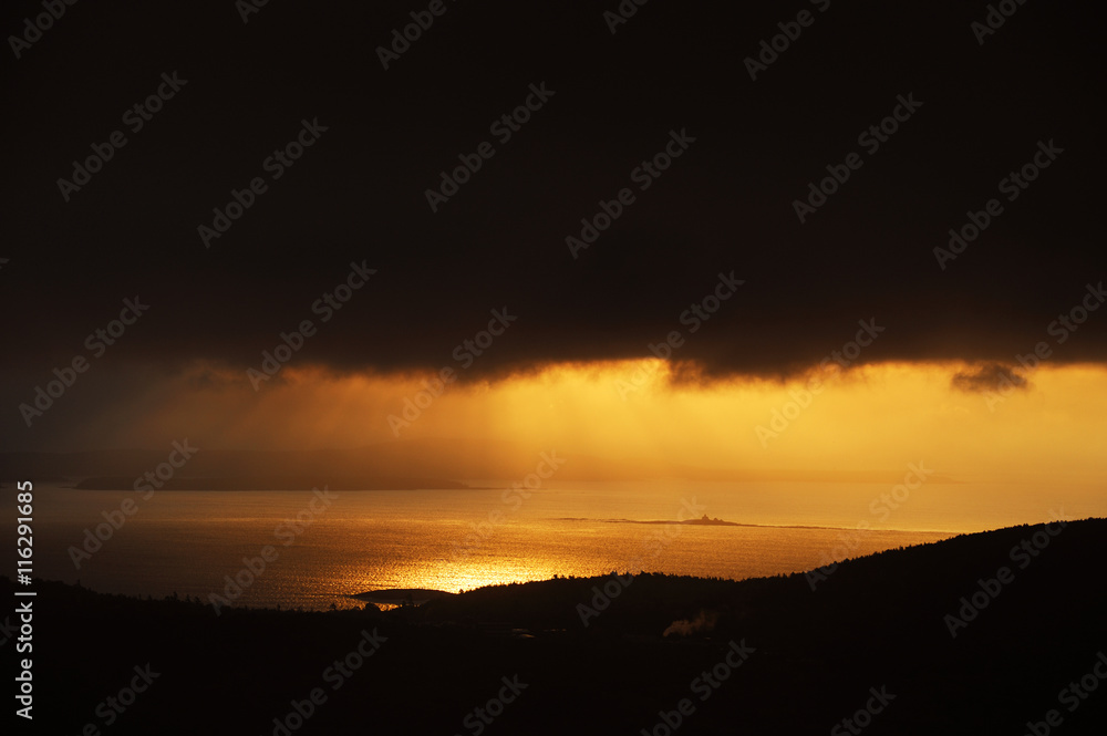 golden morning sunlight from behind cloud and shining on sea surface