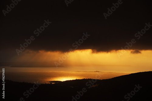 golden morning sunlight from behind cloud and shining on sea surface