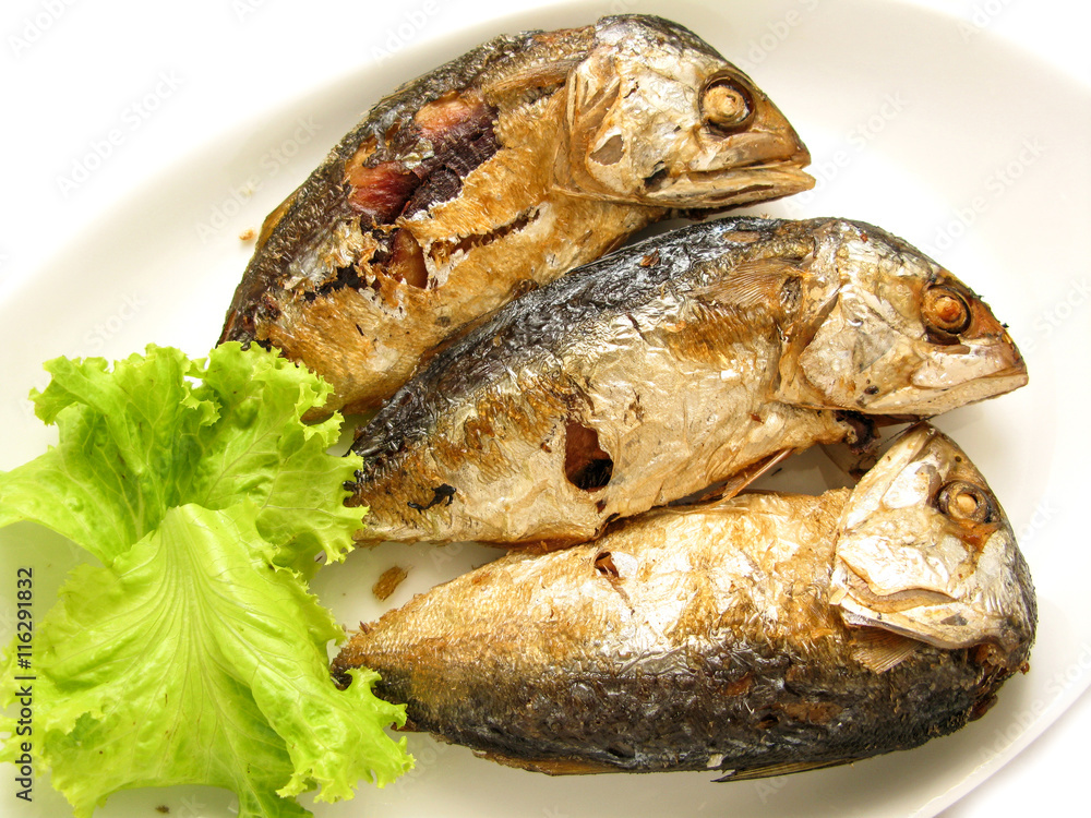 three fried mackerel put in the dish at kitchen of restaurant three fried mackerel put in the dish at kitchen of restaurant