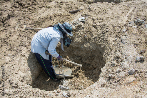 Worker digging hole with a hoe at construction site