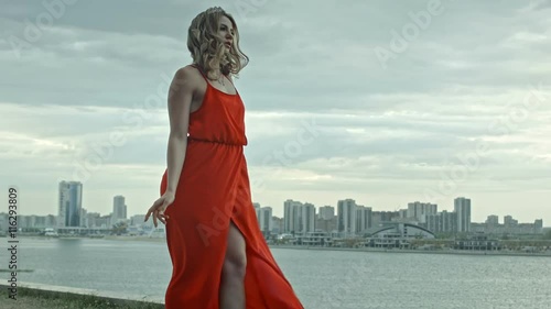 Attractive young woman in a red dress stands over the citi
