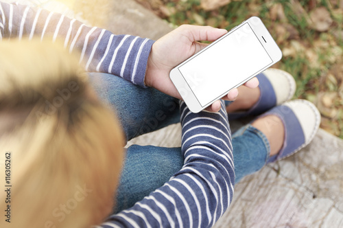 woman sitting and holding phone white screen in park