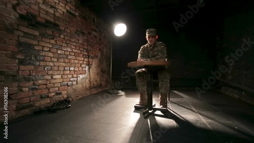 The young soldier sitting in a dirty dark room waiting for something photo