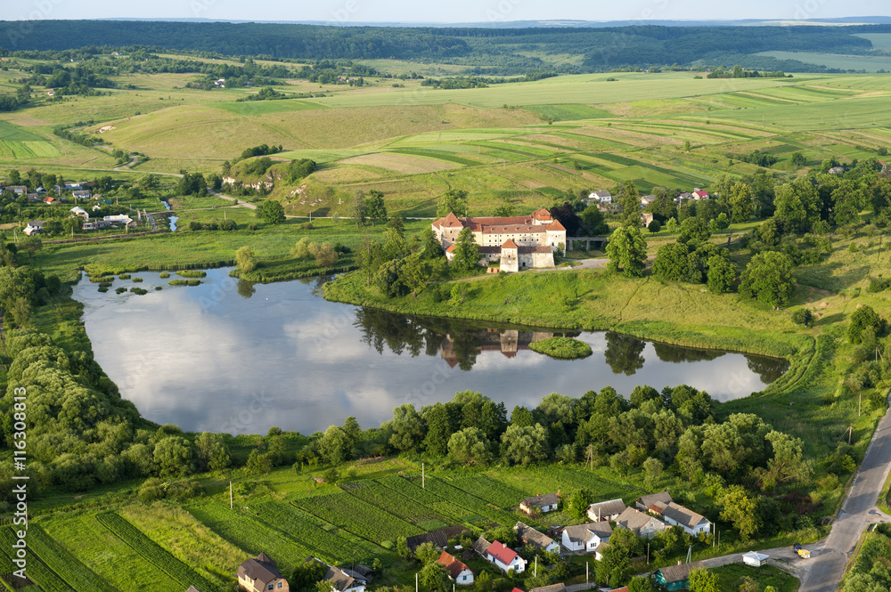 Countryside aerial view on old castle with red roof over the lake