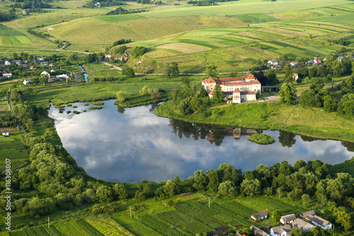 Countryside aerial view on old castle with red roof over the lake