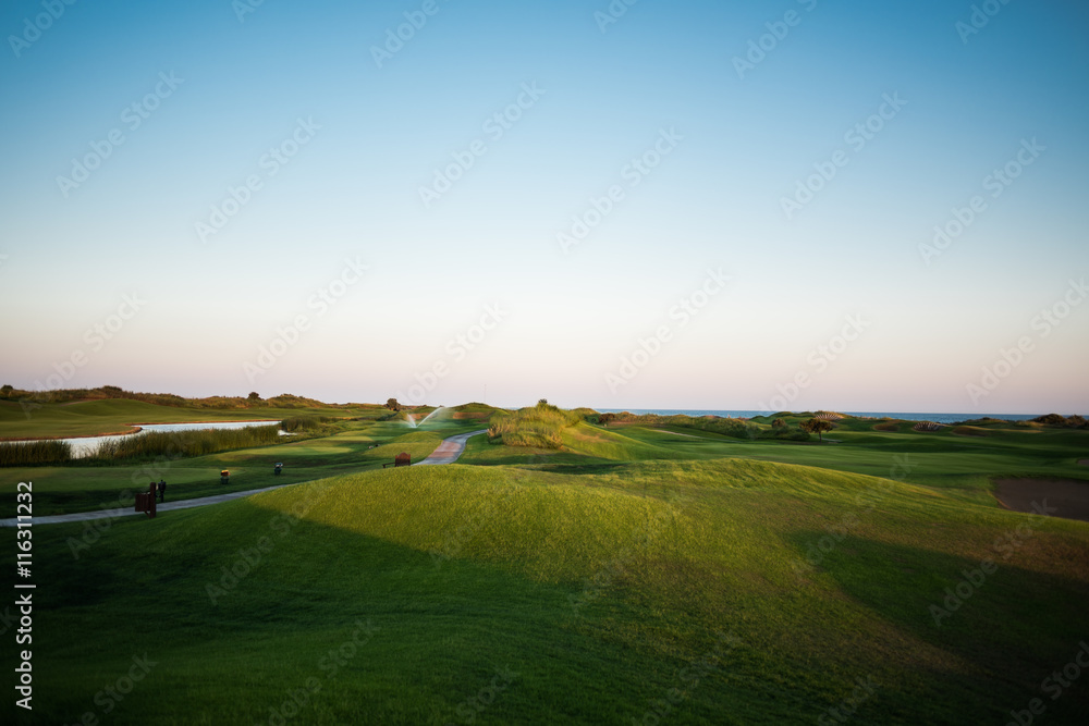 Walkway near golf course with lake hazard and sea in the background at sunset Walkway near golf course with lake hazard and sea in the background at sunset