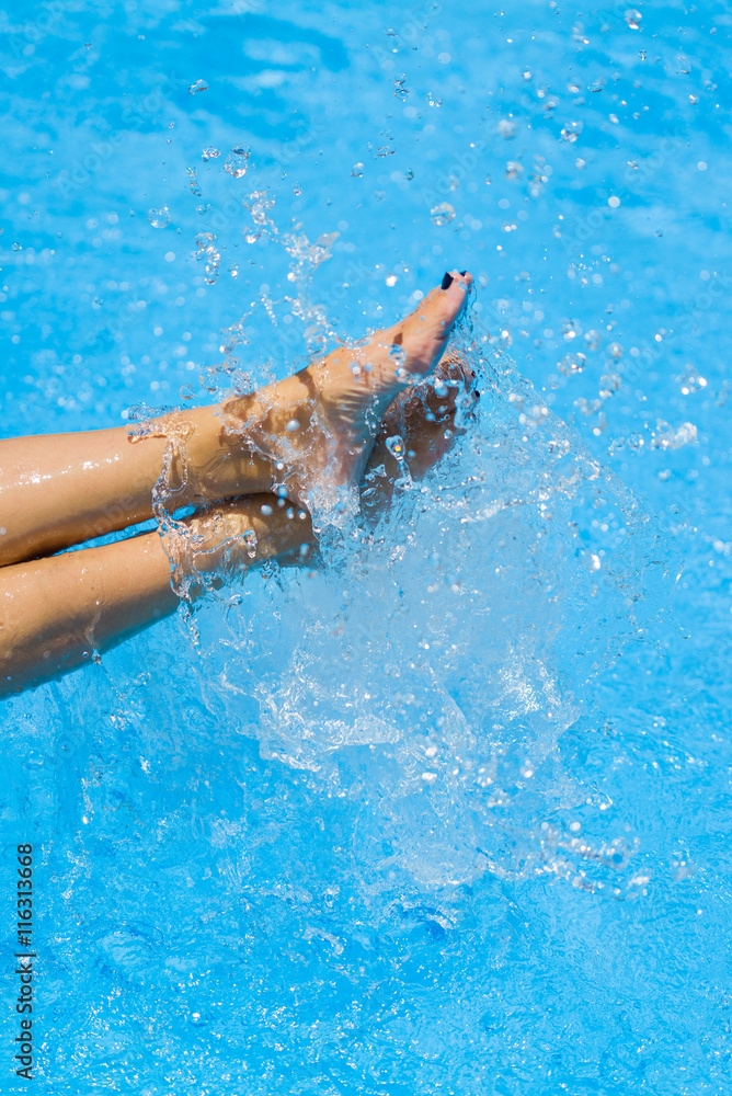 Sexy women legs splashing in tropical pool