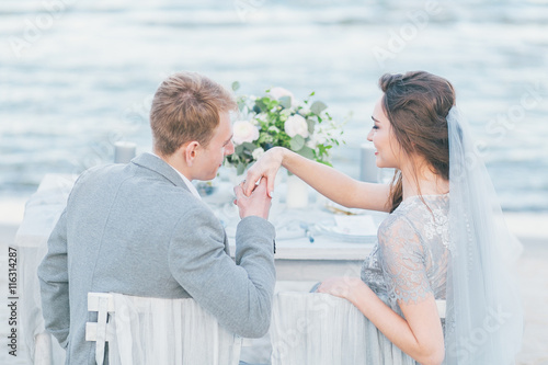 Groom wishing to kiss bride's hand at the seashore