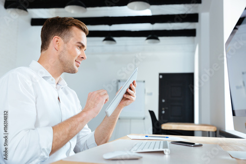 Happy young businessman using tablet in office