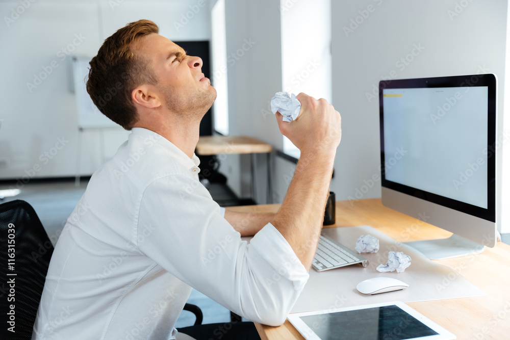 Fototapeta premium Angry stressed businessman sitting and crumpling paper in office