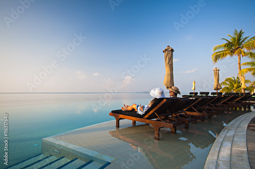 Young Couple Resting on Sun Loungers by swimming Pool