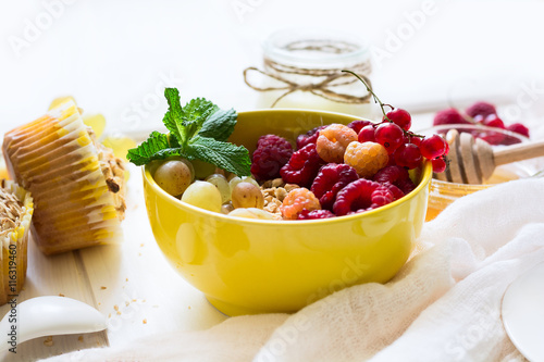 Healthy breakfast: muesli, honey, yogurt, muffins, coffee and fresh berries on white wooden background