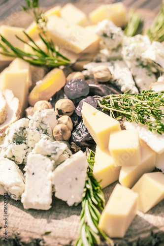 Cheese plate with cheeses Dorblu, Parmesan, Brie, Camembert and Roquefort in serving on the table from an old tree close-up photo