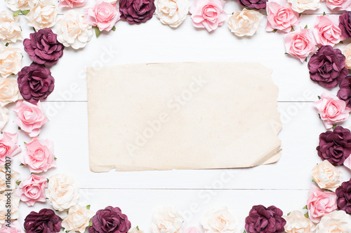 Old paper sheet with empty copyspace and roses on white wooden t