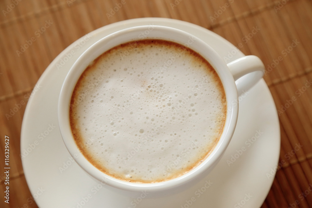 Cup of coffee with milk foam on wooden table seen from top. Cup of coffee with milk foam on wooden table seen from top.