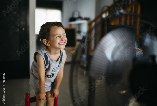 Grinning little boy standing in front of ventilator photo