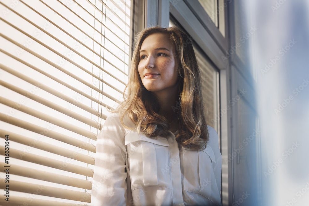 Young woman looking through window Young woman looking through window