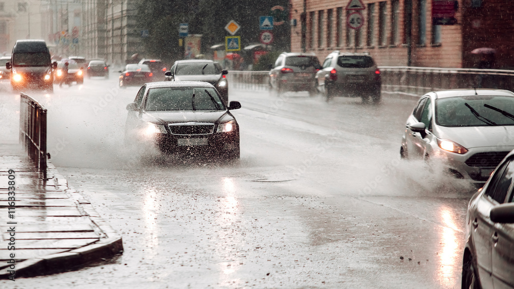 Fototapeta premium Wide screen. Moving car sprays puddle when heavy rain drops