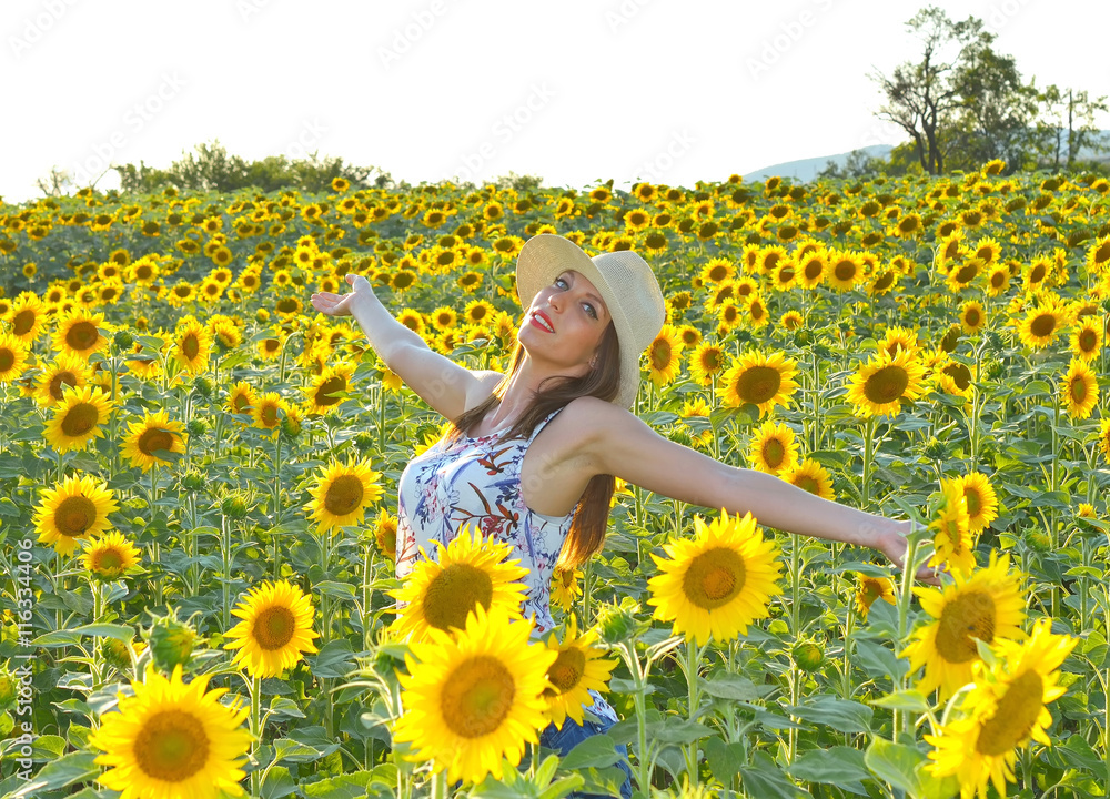 Fototapeta premium Young woman in sunflower field