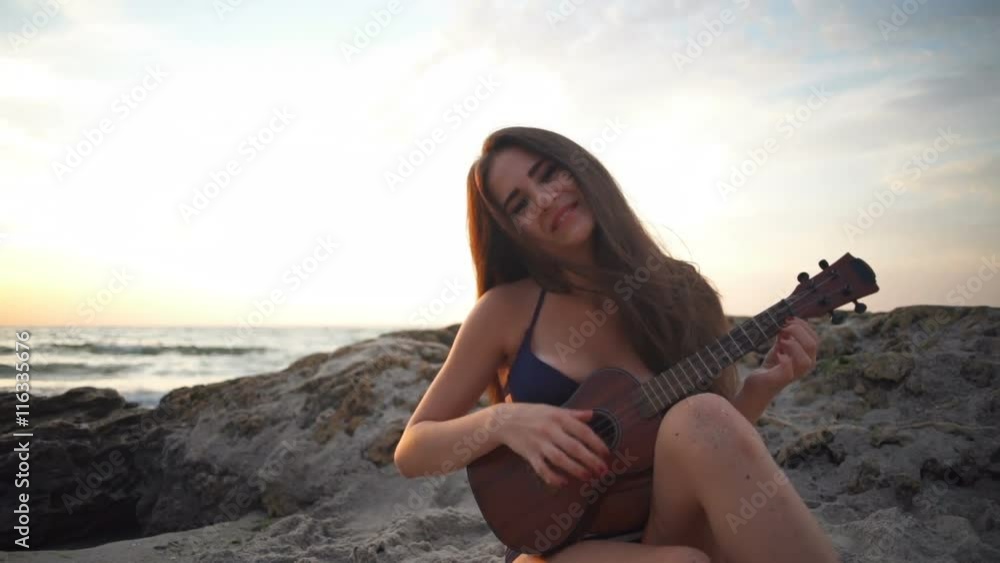 close up pretty young female plays ukulele on the beach slow motion close up pretty young female plays ukulele on the beach slow motion
