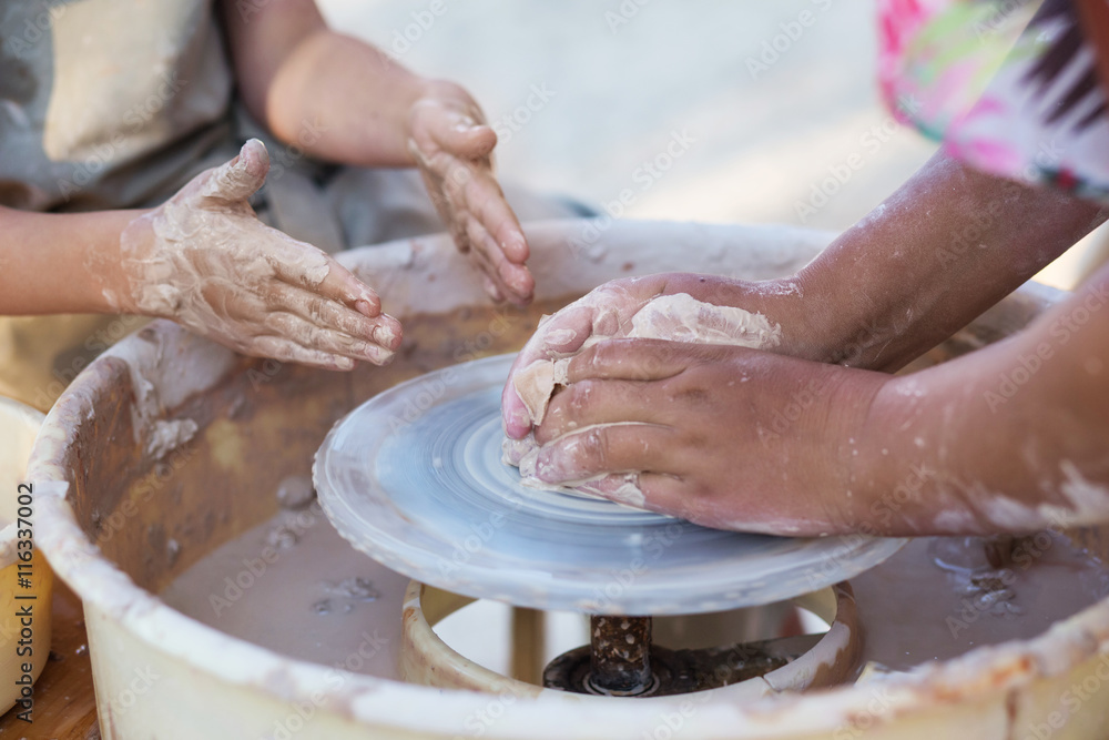 Hands of young potter, creating an earthen jar on the circle, cl