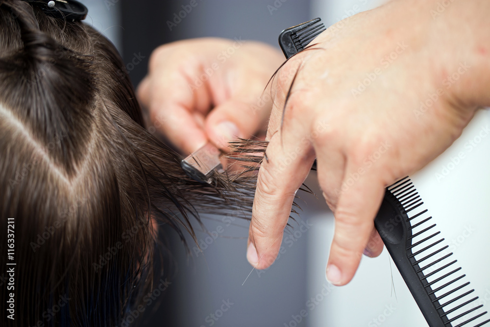 Fototapeta premium Ścinanie włosów brzytwą, dłonie fryzjera ścinającego włosy
