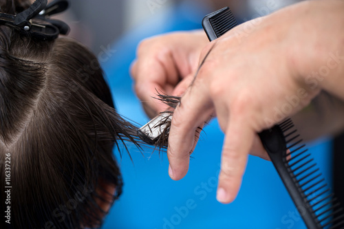 Ścinanie włosów brzytwą, dłonie fryzjera ścinającego włosy